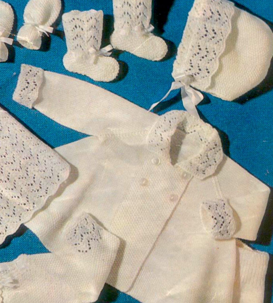 Close-up of baby pram coat in moss stitch with lace panels. Restored vintage 1960s baby layette knitting pattern in 3-ply.
