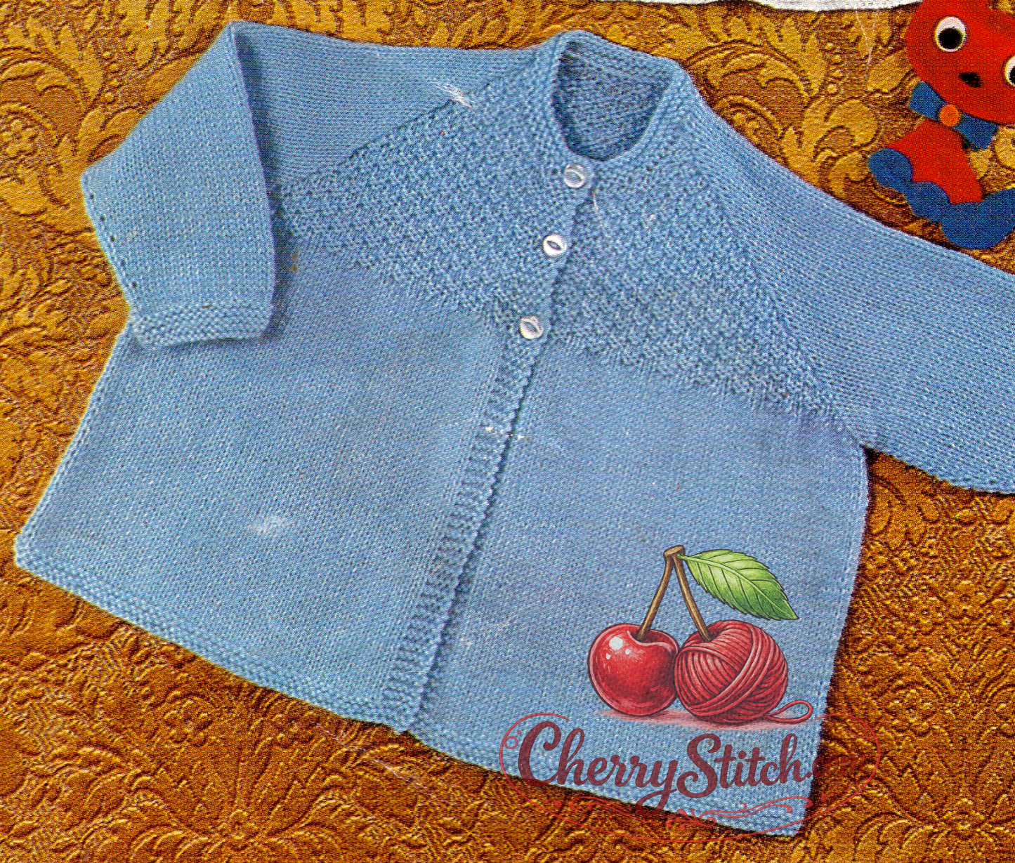 Close-up of blue baby matinee coat with richly textured stitch panel on front chest and smooth stocking stitch body. Restored vintage 1960s knitting pattern in 4-ply, raglan sleeves.