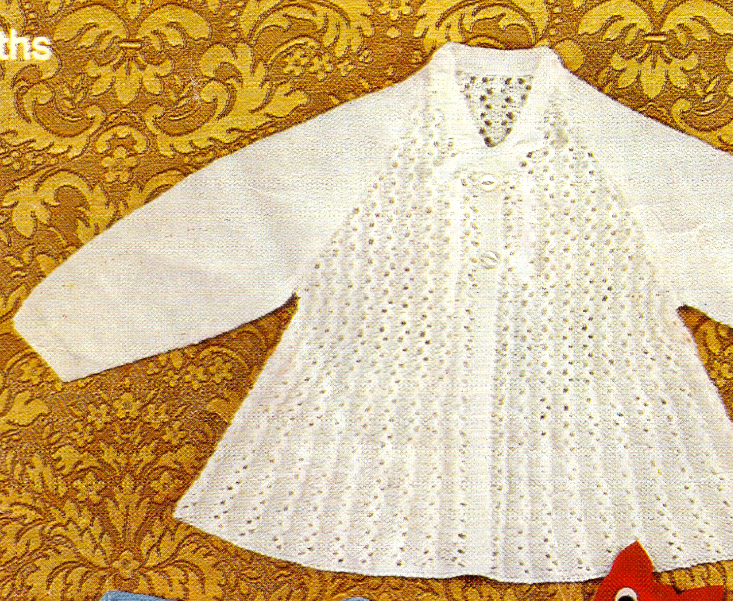Close-up of white baby matinee coat with delicate all-over lace stitch on front and back. Restored vintage 1960s knitting pattern in 4-ply, raglan sleeves.