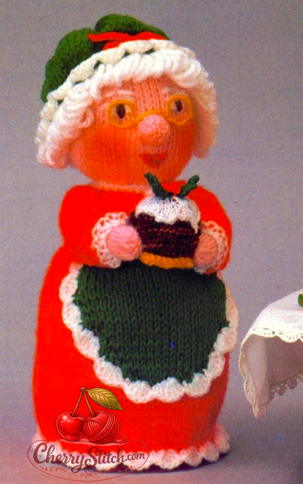 Detail view of vintage Woolly Wotnots Mother Christmas and Pudding — soft stuffed toy doll, 12'' (30 cm) tall. Charming festive character holding a plate with Christmas Pudding. DK, 4ply and chunky yarn. Wonderful Christmas gift idea and home decoration. Intermediate knitting.

