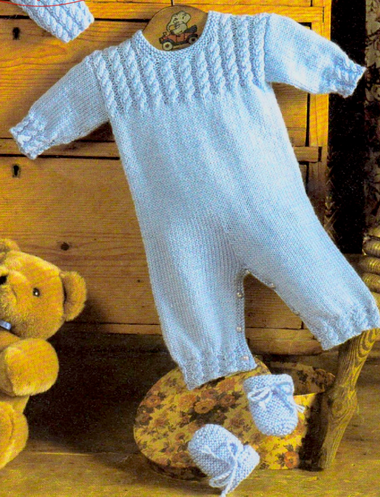 Close-up of knitted baby boy romper and mitts with cable details – restored vintage 1980s layette pattern