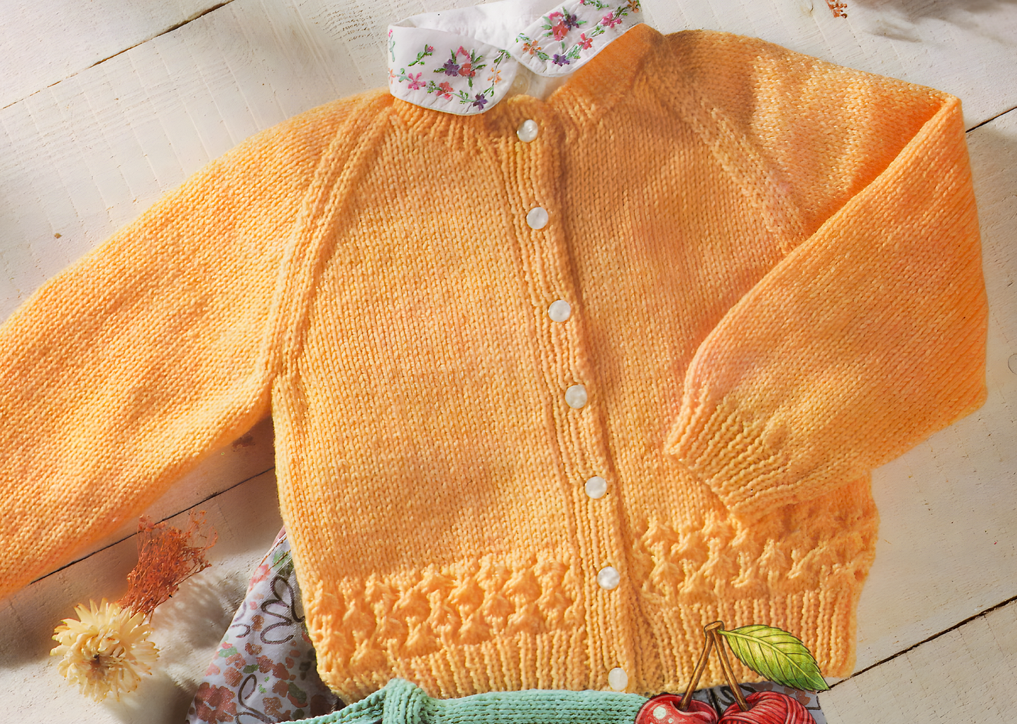 Close-up of baby round-neck cardigan – vintage 1980s raglan knitting pattern DK