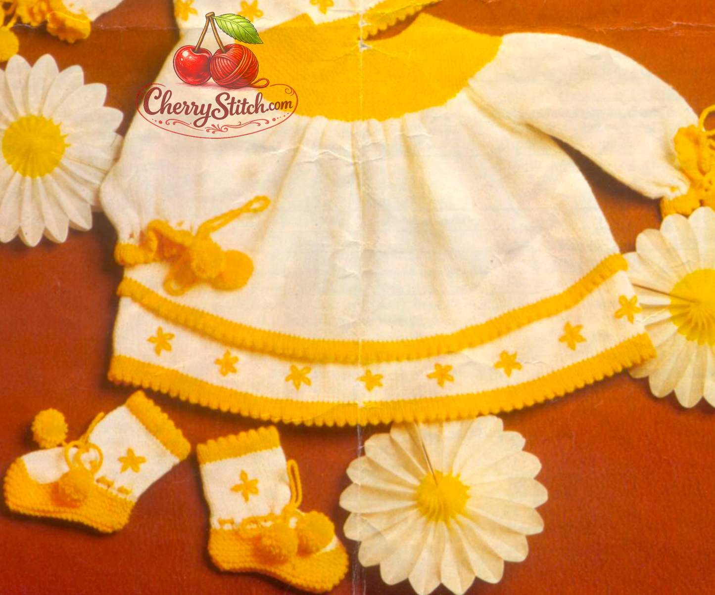 Close-up of dress and bootees with golden yellow hem contrast and lazy daisy embroidery – restored vintage 1970s baby layette knitting pattern in 4-ply