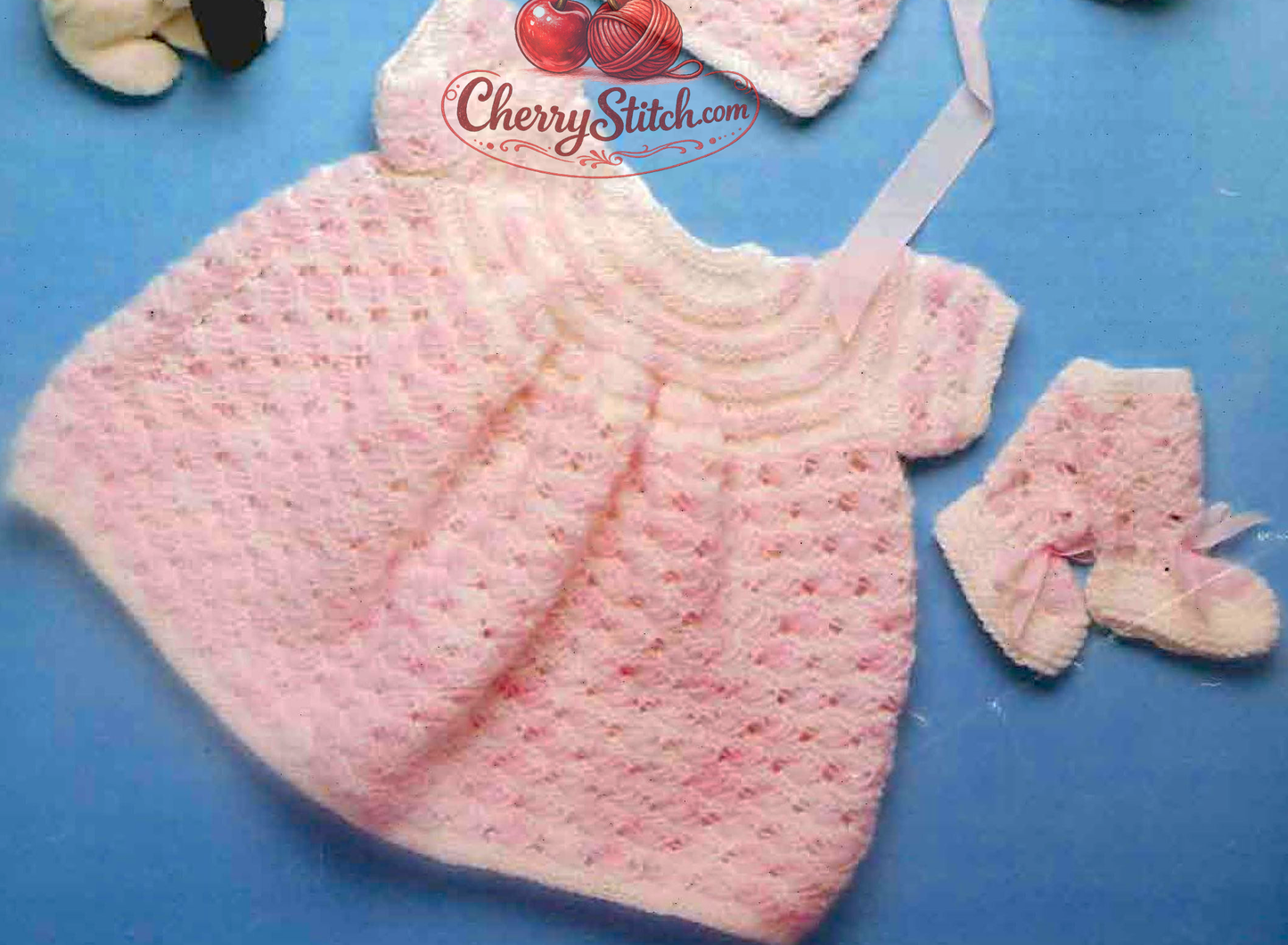 Close-up of baby girl's knitted dress flared skirt and bootees – vintage 1980s layette knitting pattern DK