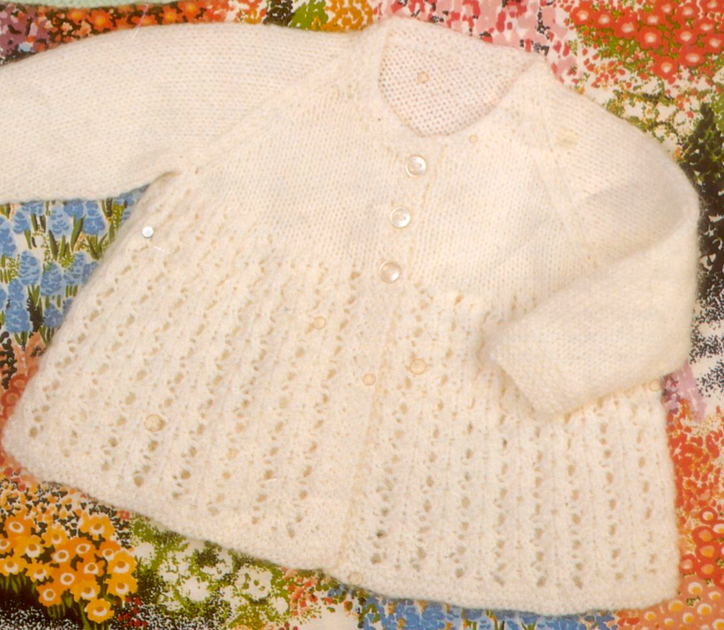 Close-up of round neck version – restored vintage 1970s baby lacy matinee coat knitting pattern with raglan sleeves in DK