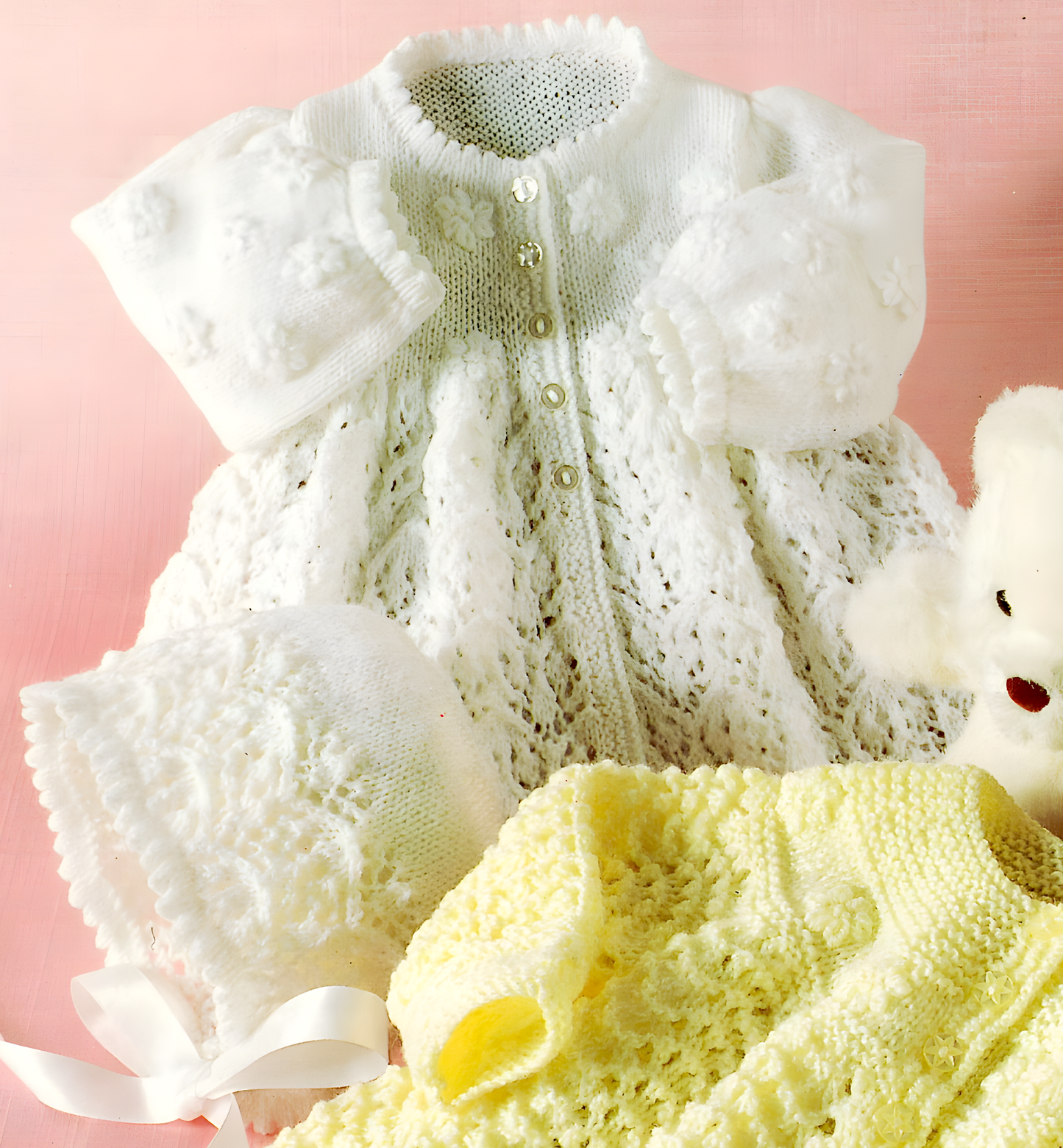 Close-up of white knitted baby matinee jacket and bonnet in lace stitch – restored vintage 1990s pattern in 3-ply